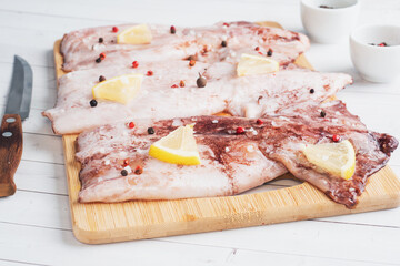 Raw squid carcass with spices and lemon ready for cooking on a wooden cutting board. copy space. Top view