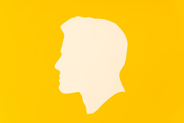 Profile of a man's head cut out and paper on a yellow background