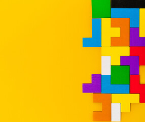 Geometric shapes made of wood in different colors, top view. Desktop constructor in the tetris format. Copy space.