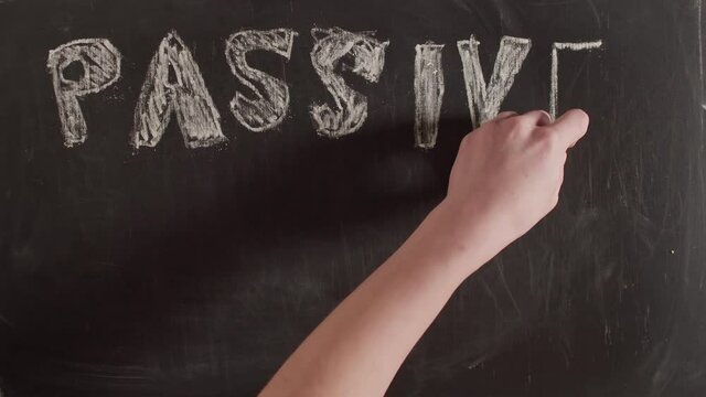 The phrase passive income is written on a chalkboard by hand, timelapse. On the blackboard is written in large letters passive income.