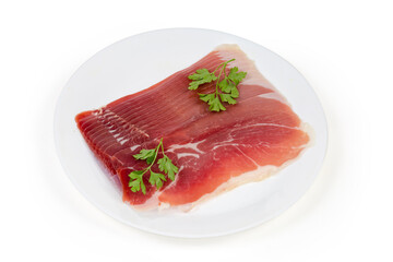 Thin slices of jamon with parsley twigs on white dish