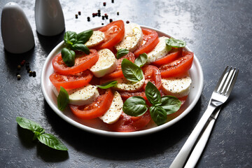 Caprese is a tomato and mozzarella appetizer. Traditional Italian salad on a concrete background with space for text.
