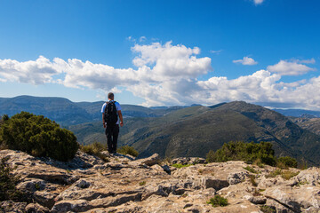 Naklejka premium Hikers walking on mountains, in a sunny spring day. In La vall de laguar, Alicante (Spain)