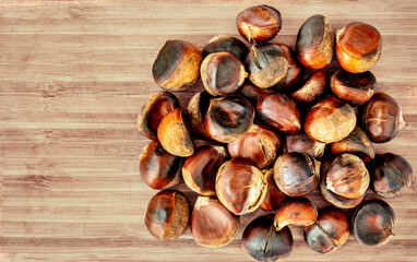 Obraz premium Horse chestnuts on a wooden cutting board. Cracked Roasted Chestnuts with a shell Top view. Autumn food concept.