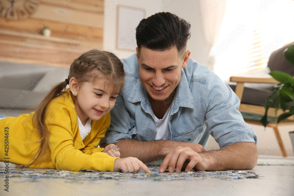 Poster happy father and his daughter playing with puzzles on floor at home