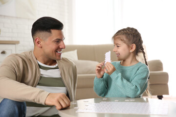 Fototapeta premium Happy father and his daughter playing with puzzles at home
