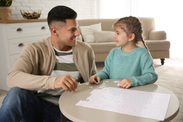 Happy father and his daughter playing with puzzles at home