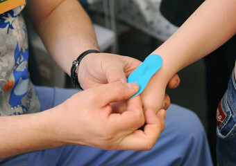 Child with hand injury during kinesio taping therapy. Kinesiology, physical therapy, rehabilitation banner.