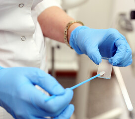 A gynecologist in blue gloves is taking an analysis for research. Gynecologist taking a smear.