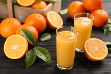 Delicious orange juice and fresh fruits on black wooden table