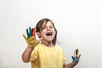 Happy toothless little girl with painted hands laughing and having fun - Little girl who is painting her hands with smiley faces and numbers - Childhood, colors and happiness concept - Copy space  - Powered by Adobe