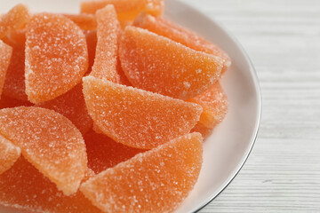 Tasty orange jelly candies on white table, closeup