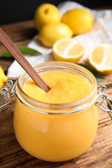 Delicious lemon curd in glass jar on wooden table