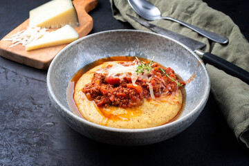 Modern style traditional Italian polenta alla sarda con salsiccia with ground meat ragu and pecorino served as close-up on a Nordic design bowl
