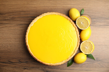 Delicious homemade lemon pie and fresh fruits on wooden table, flat lay