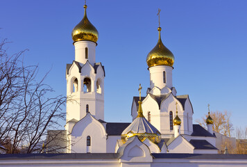 Church of the Archangel Michael in Novosibirsk. The towers of the Orthodox church in the Old Russian architectural traditions with golden domes and crosses against the blue sky. Siberia, Russia