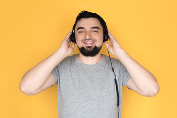 Handsome male with headphones on head listening to the music and smiling