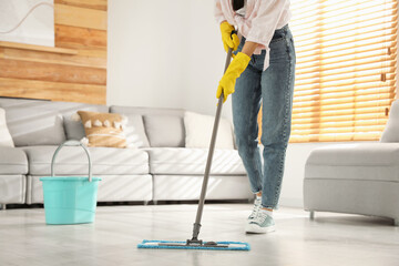 Woman cleaning floor with mop at home, closeup