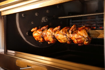 Grilling whole chickens in rotisserie machine, closeup