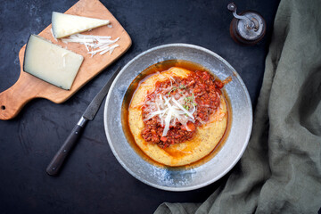 Modern Style traditionelle italienische Polenta alla Sarda con Salsiccia mit Hackfleisch Ragout und Pecorino serviert served als Draufsicht in einer Nordic Design Schale