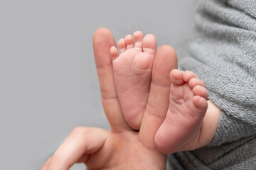 The father is holding the feet of the newborn baby. grey colour. tenderness. Father's day concept.