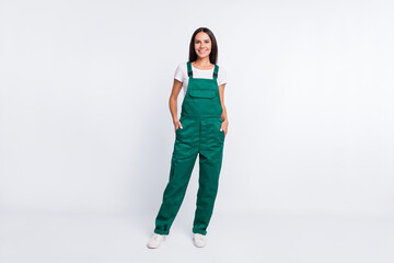Photo of charming cool lady hands pockets look camera wear green overall isolated white color...