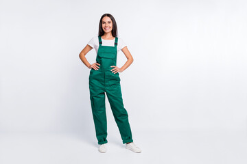 Photo of pretty positive lady hands hips look camera wear green overall isolated white color...