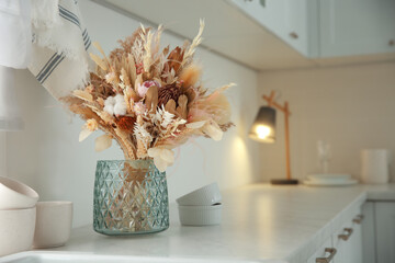 Bouquet of dry flowers and leaves on countertop in kitchen. Space for text