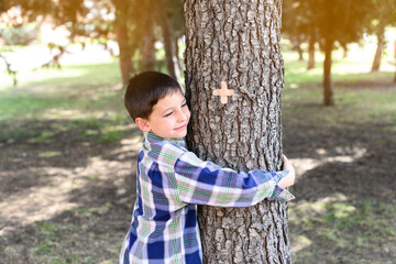 Happy child hugging a tree trunk in a forest