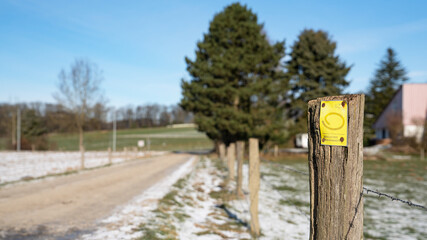 LINDLAR, GERMANY - FEBRUARY 14, 2021: Long distance hiking trail Bergischer Panoramasteig during winter with focus on the typical waymark on February 14, 2021 in Germany