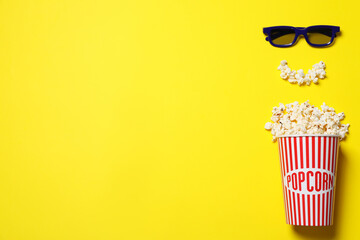 Popcorn and 3d glasses on yellow background, flat lay with space for text. Cinema snack