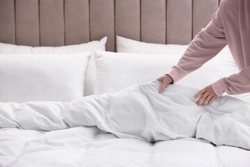 Fototapeta na wymiar Woman making bed with stylish linens in room, closeup