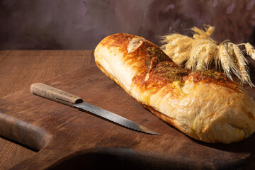 Breads, beautiful stuffed breads placed on wooden surface with branch of wheat, dark abstract background, selective focus.
