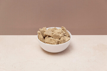 Halva slices in a white cup on a beige background