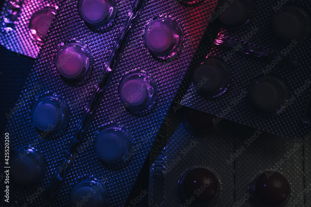 Poster Pills or drugs in a package under neon light on a dark background pattern for design..