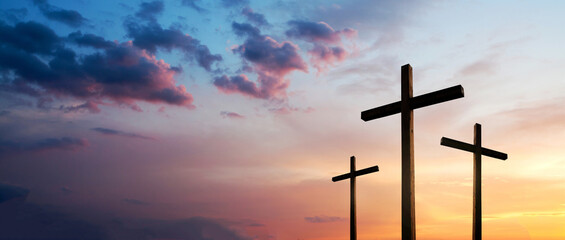 Easter concept. Cross of Jesus Christ empty over dramatic sunrise sky panorama with sclouds.