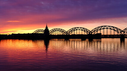 Dawn over the Daugava, the sun illuminates the railway bridge in Riga