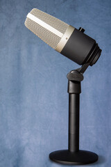 professional condenser microphone with pedestal isolated with blue spotted background, selective focus.