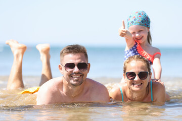 Obraz premium Family with little girl lying in sea