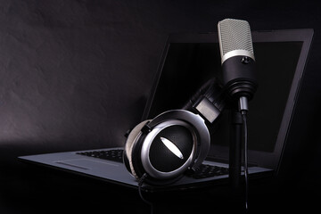 home work, professional condenser microphone, headphones and computer on dark surface, dark...
