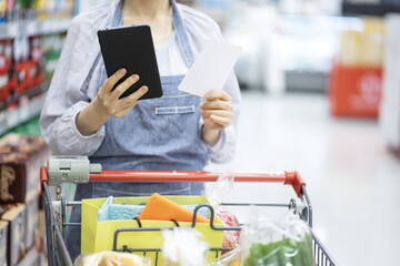 Woman shopping with shopping list and digital tablet in mart