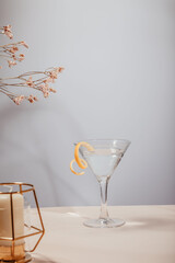 Glass of lemon drop martini cocktail on table against grey background