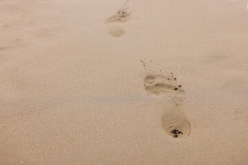 Fototapeta na wymiar Closeup of footprints from bare feet on sand