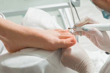 A Podiatrist doctor who takes care of a woman's toenails. Cosmetic procedures of the feet - obrazy, fototapety, plakaty