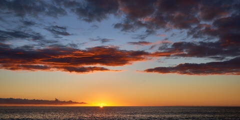 Panoramic view of the dramatic sunset sky with dark clouds over ocean in Hawaii.