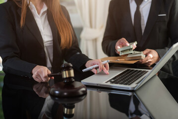 Justice and law concept.Male judge in a courtroom the gavel, working with digital tablet computer on wood table in sun light.