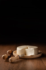 Cheese, Minas cheese from Brazil on a wooden plate with cheese accessories on wooden surface, black background, selective focus.