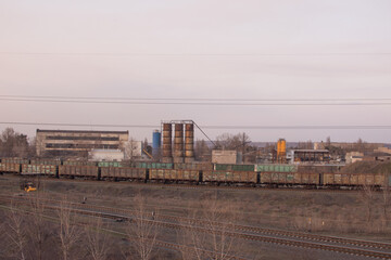 Industrial site, railway cars, buildings of industrial premises. Railway tracks. In the evening at sunset.