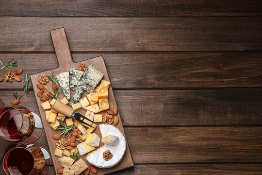 Cheese plate with rosemary and nuts on wooden table, flat lay. Space for text