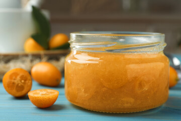 Delicious kumquat jam in jar on light blue wooden table, closeup